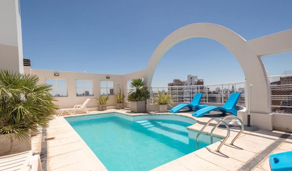 罗萨里奥乌尔奇萨公寓&套房酒店的一座带蓝色椅子的建筑屋顶上的游泳池