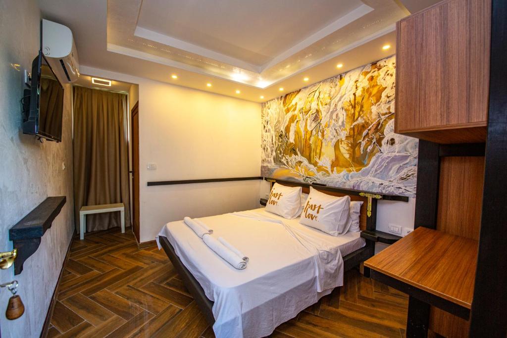 斯库台Hotel Legjenda的酒店客房设有一张床,墙上挂有绘画作品