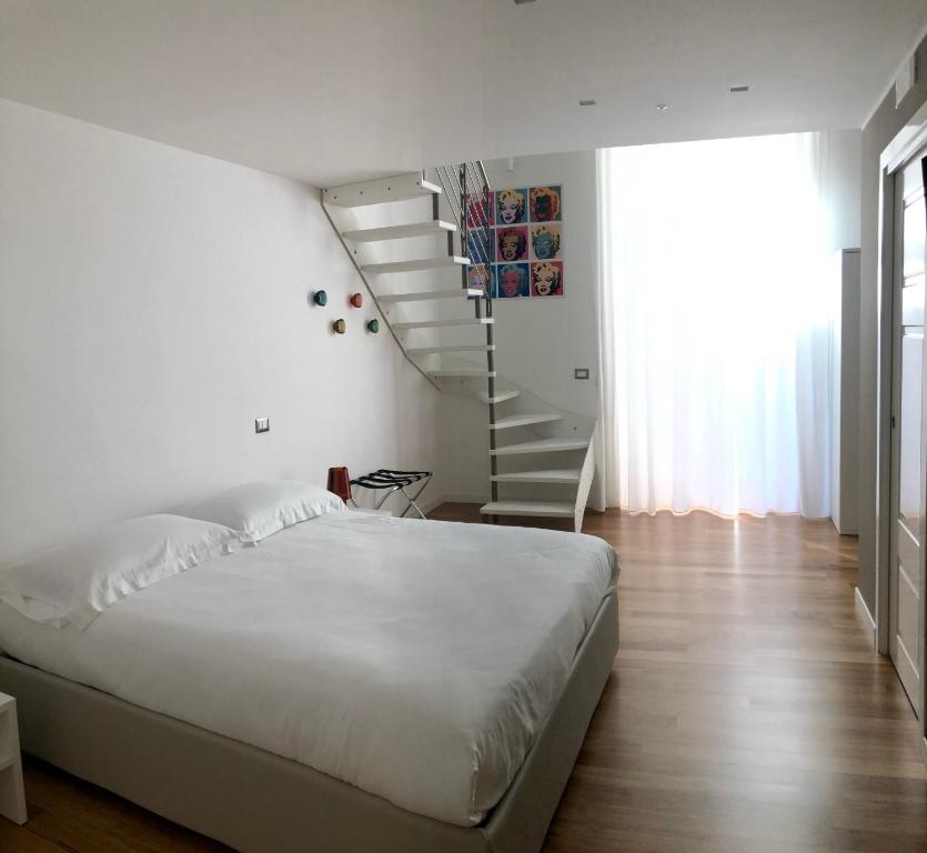 塔兰托Lo Schiaccianoci B&B的一间白色的卧室,配有床和楼梯