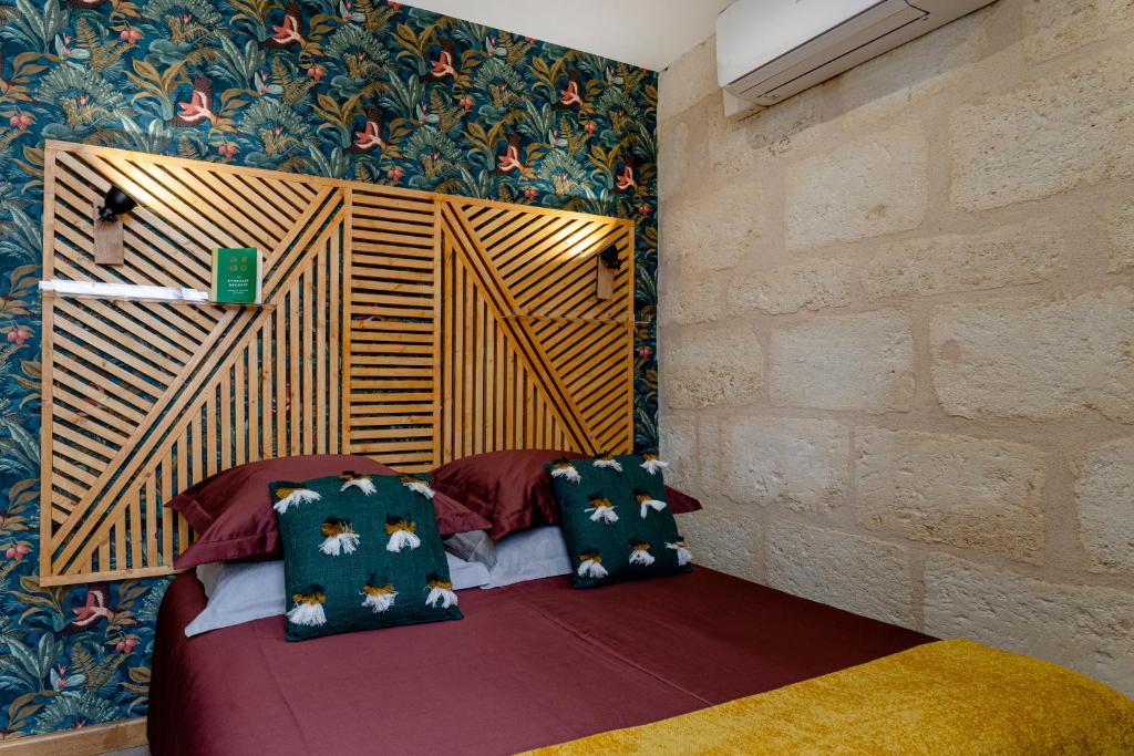 波尔多Hôtel Particulier - Bordeaux St Jean的客房配有带枕头的床铺和墙壁。