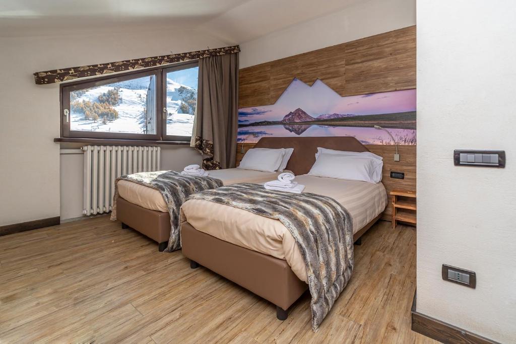 塞斯特雷Hotel Du Col的一间卧室设有两张床,墙上挂着一幅画