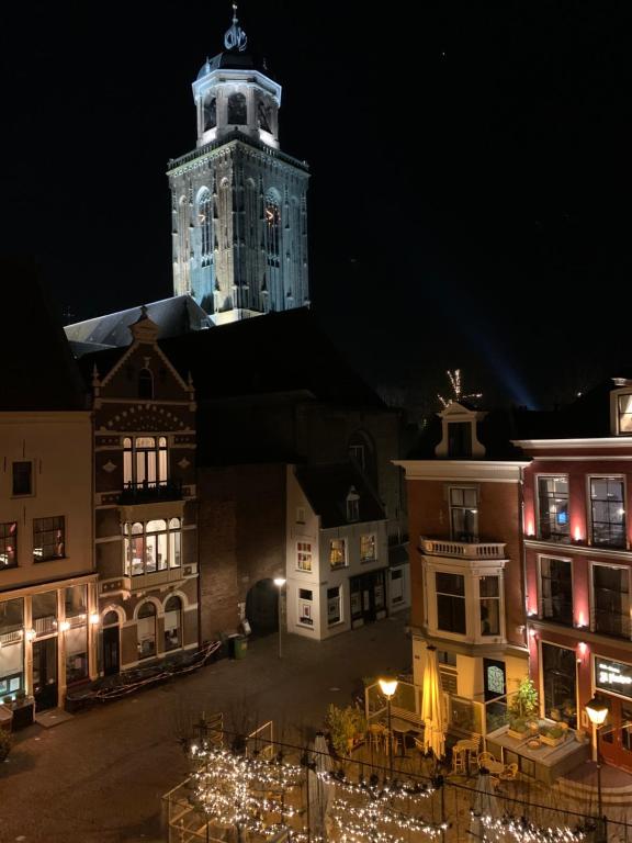 迪温特Hostel Deventer, Short Stay Deventer, hartje stad, aan de IJssel,的一座在晚上设有钟楼的大型建筑