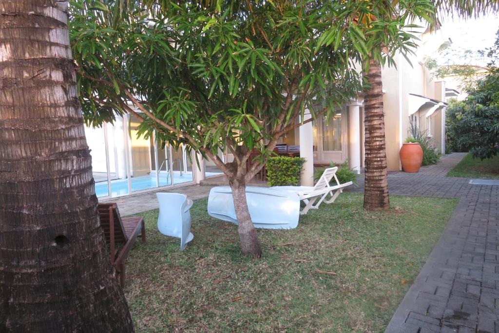 蓝海湾Villa De Rouba的院子里的一组椅子和一棵树