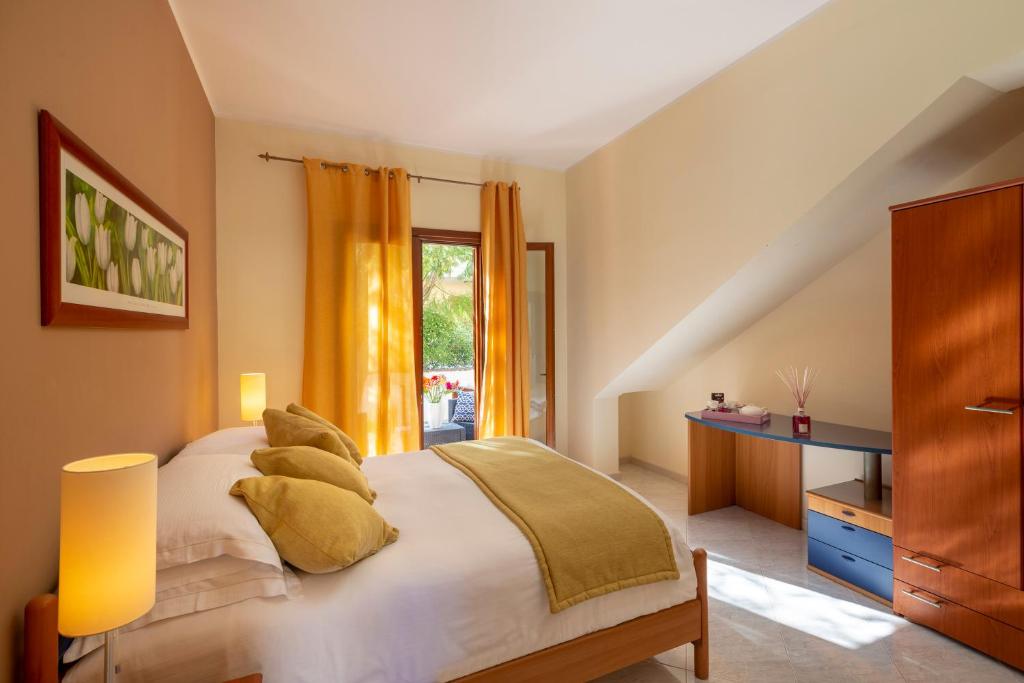 圣维托罗卡波Residence Smeraldo的卧室配有带枕头的床铺和窗户。