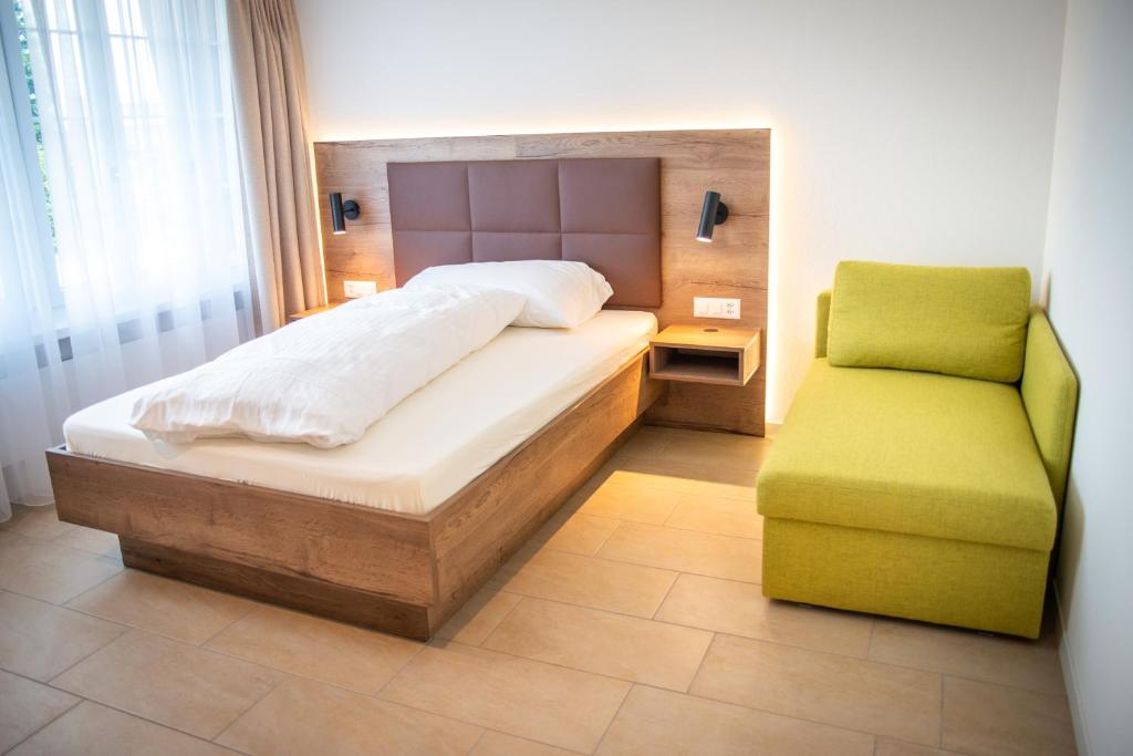 Uznach舒琛豪斯酒店的一间卧室配有一张床和一把绿色椅子
