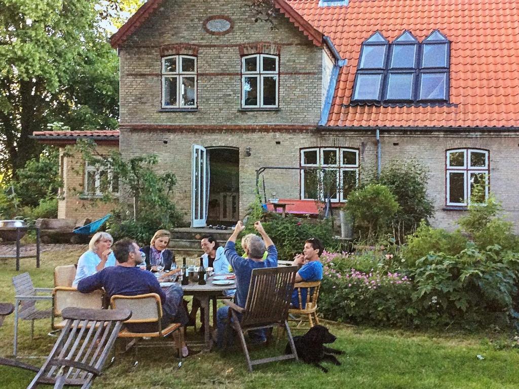 森讷堡10 person holiday home in S nderborg的一群人坐在房子前面的桌子上
