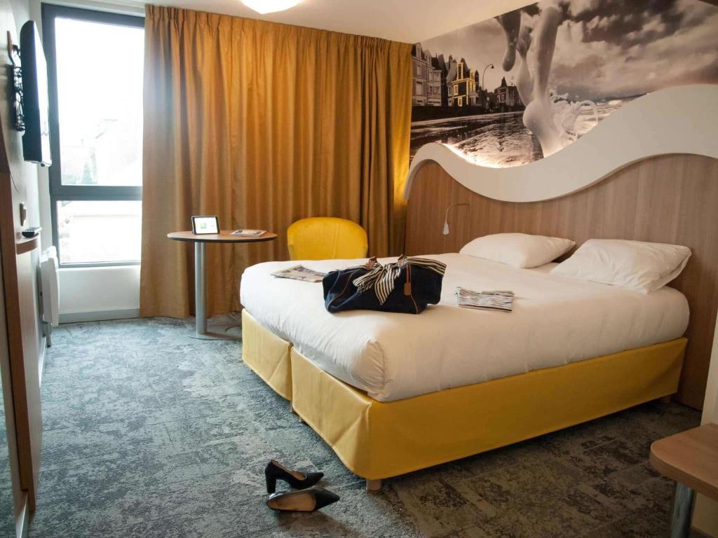 圣马洛圣马洛港宜必思尚品酒店的酒店客房设有一张床,墙上挂有绘画作品