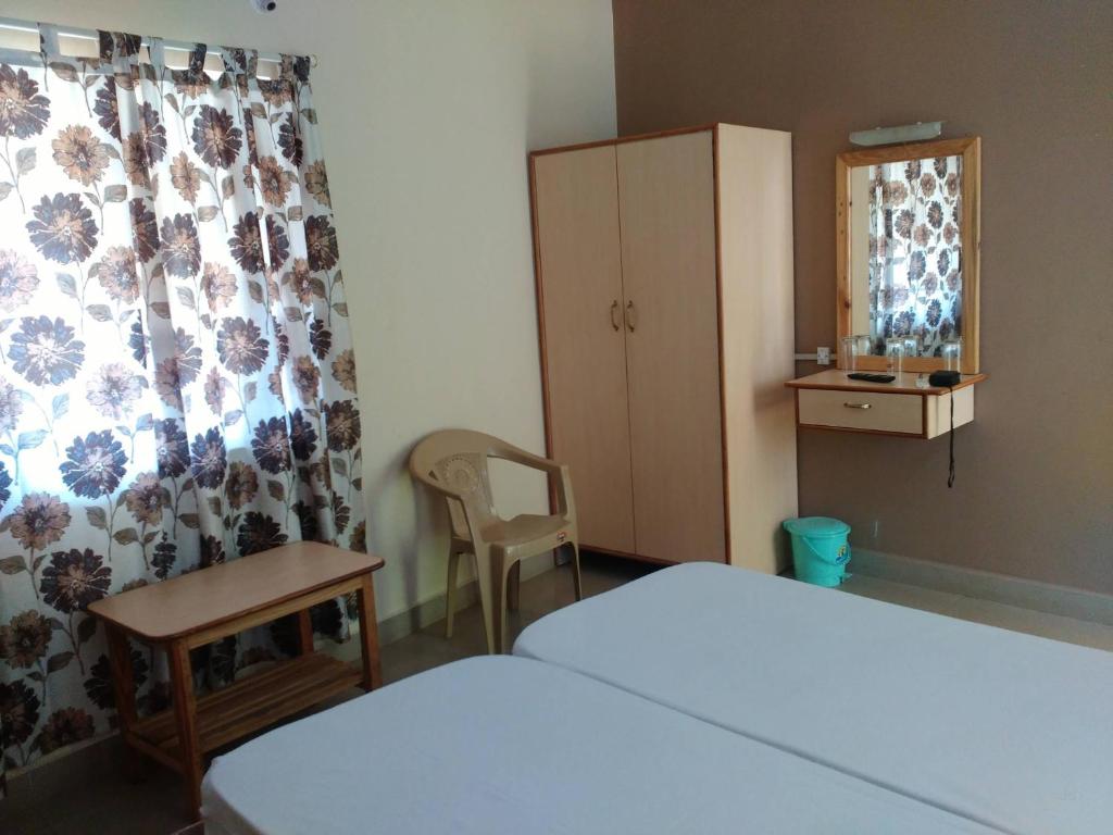 瓦斯科达伽马HOTEL RUKMINI的一间卧室配有一张床、一把椅子和一个橱柜