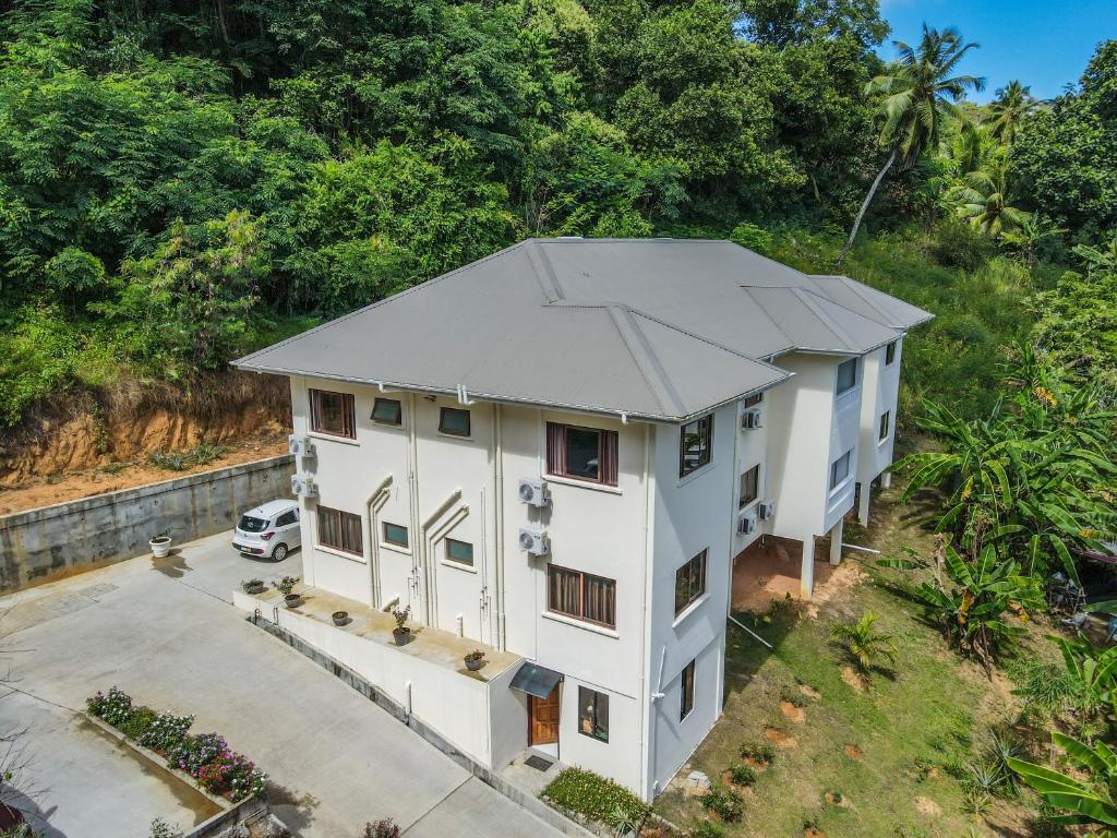 马埃岛贝拉扎尔区Kanasuk Self catering Apartments的享有白色房子顶部的景色,设有停车场