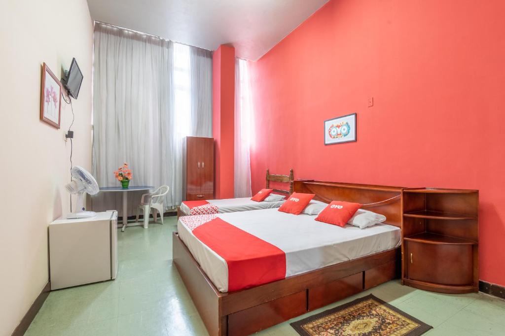 贝洛奥里藏特OYO Hotel L'Espace - Jaraguá Belo Horizonte的一间卧室设有红色的墙壁和一张带红色枕头的床