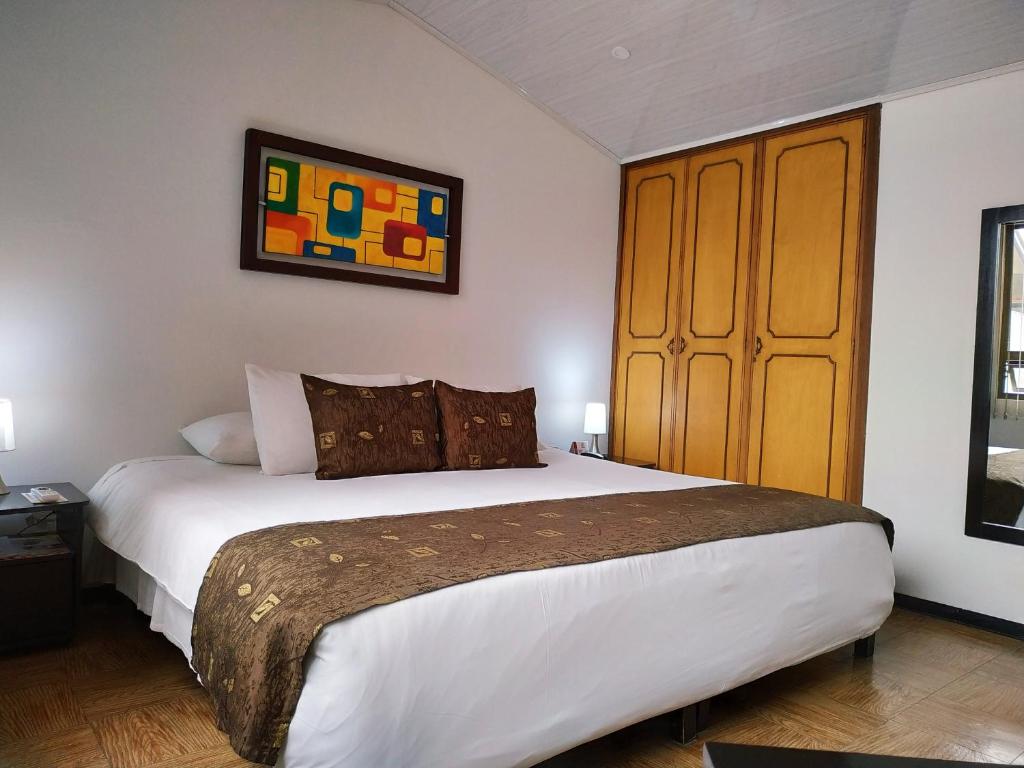 波哥大Hotel Confort Bogota的一间卧室配有一张大床和一个木制橱柜