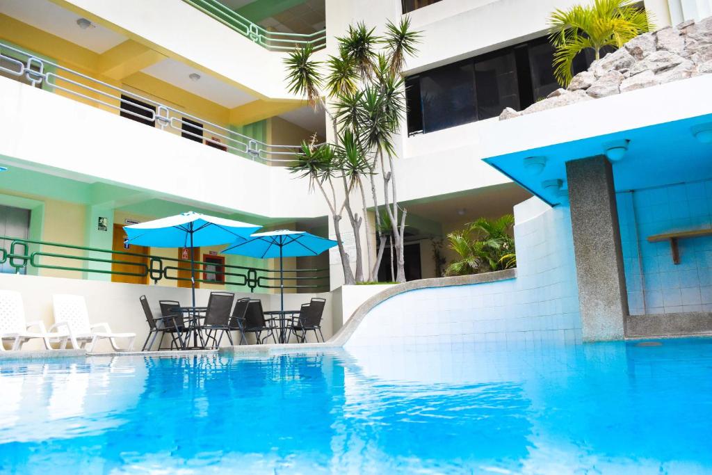 萨利纳斯蓝湾酒店的一座带椅子和遮阳伞的游泳池位于一座建筑旁边