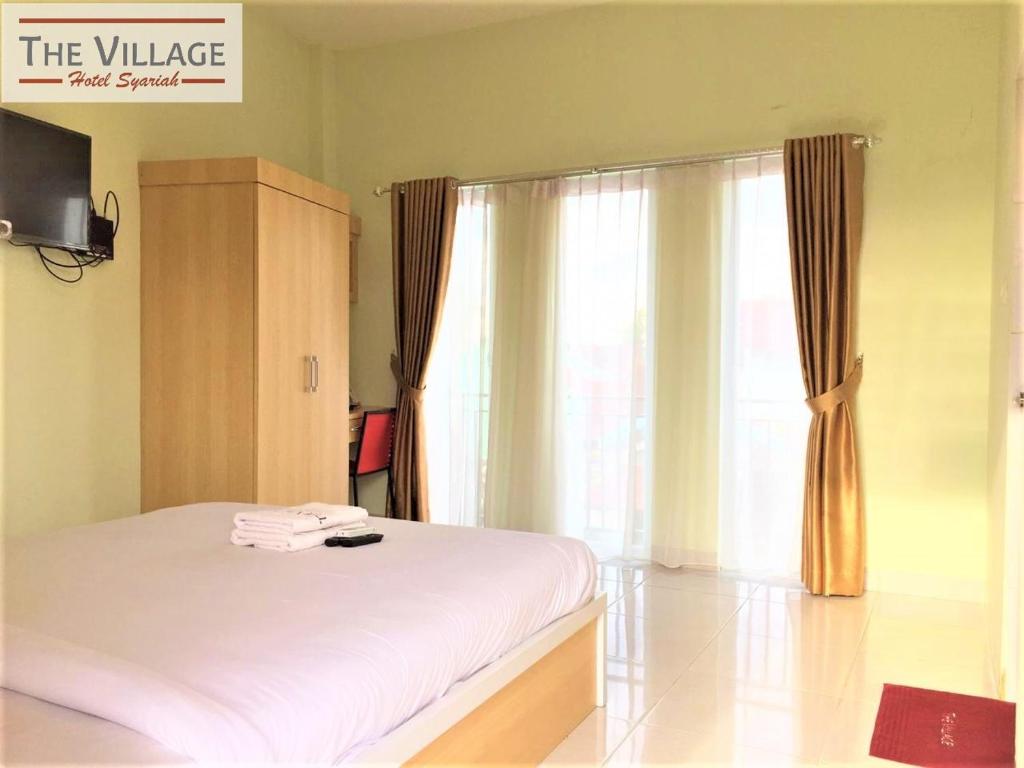 北干巴鲁Hotel The Village Syariah的卧室配有白色的床和窗户。