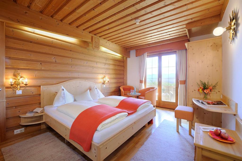 米尔施塔特阿尔卑罗斯自然酒店的卧室配有一张床铺,位于带木墙的房间内