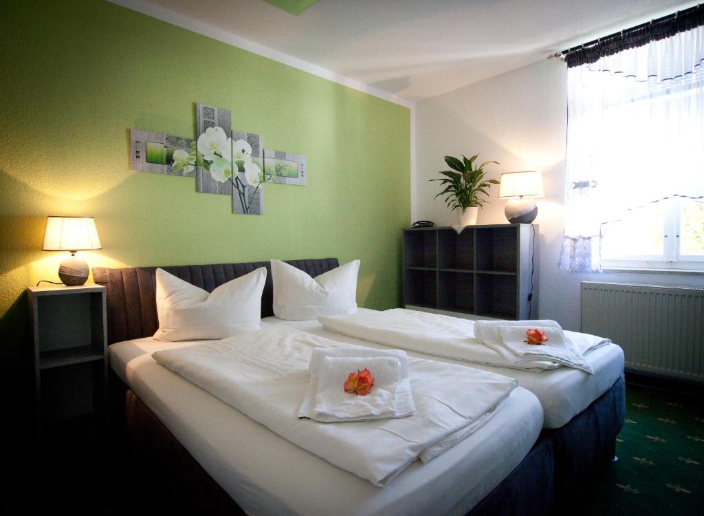 Thum图姆莱茨盖勒旅馆的一间卧室配有两张床,提供白色的床单和鲜花