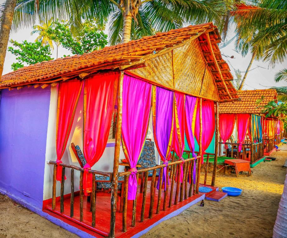 阿姆波尔GoYm Resort的海滩上一座带五颜六色窗帘的小房子