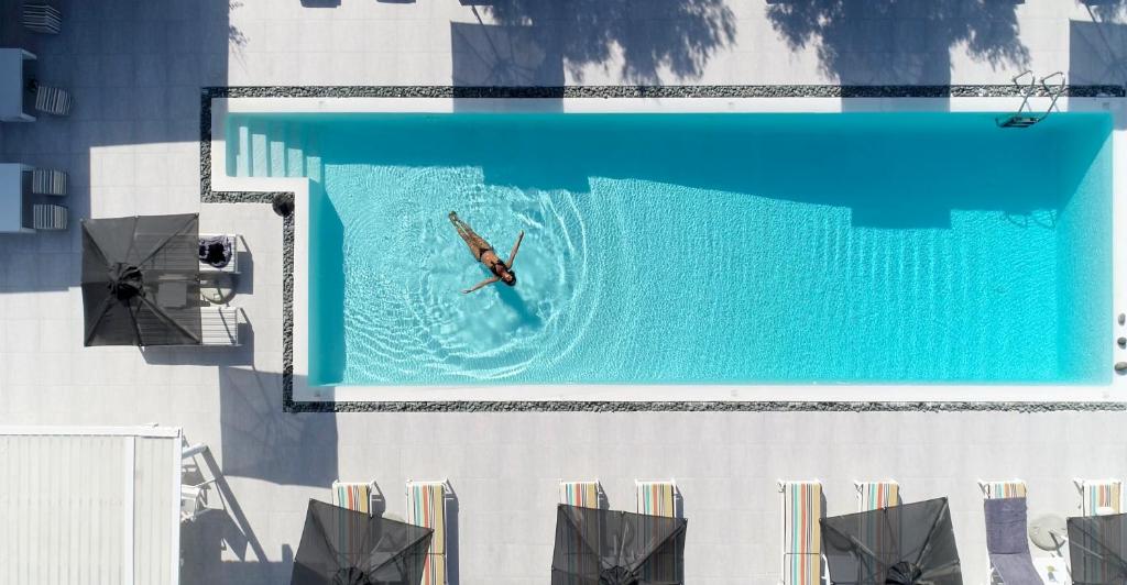 纳乌萨Naoussa Hills Boutique Resort- Adults Only (13+)的在建筑物顶部的游泳池游泳的人