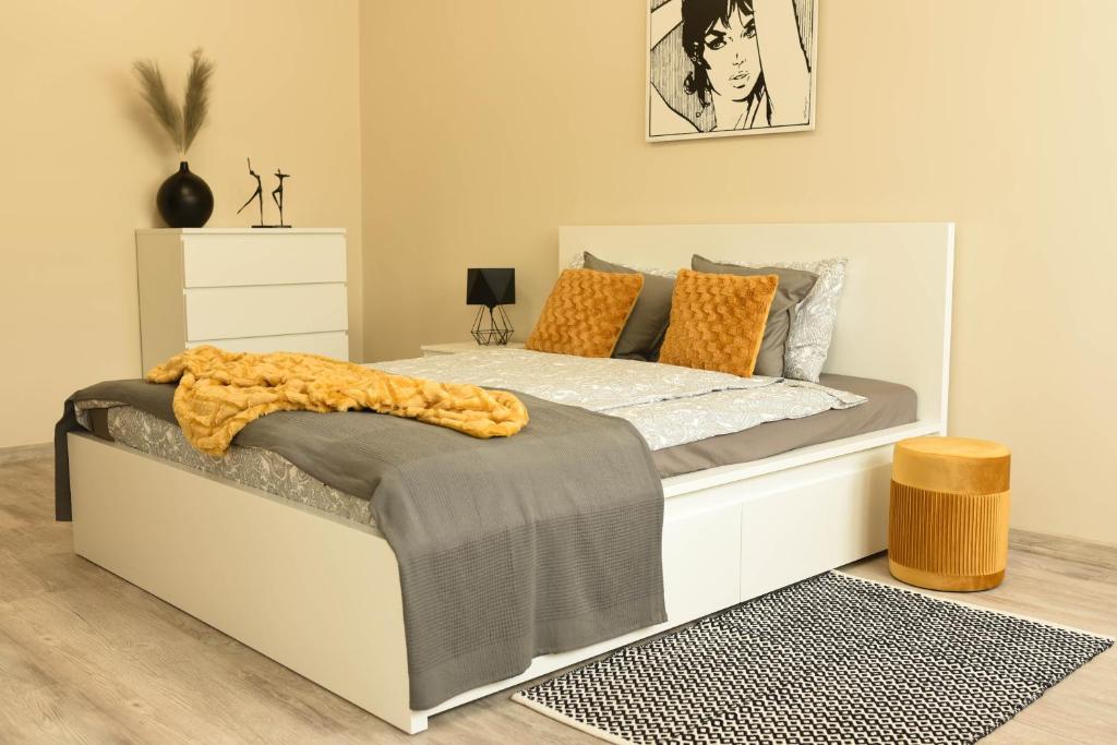 杰尔若纽夫Apartament Studio Klasztorna的卧室配有带橙色枕头的白色床