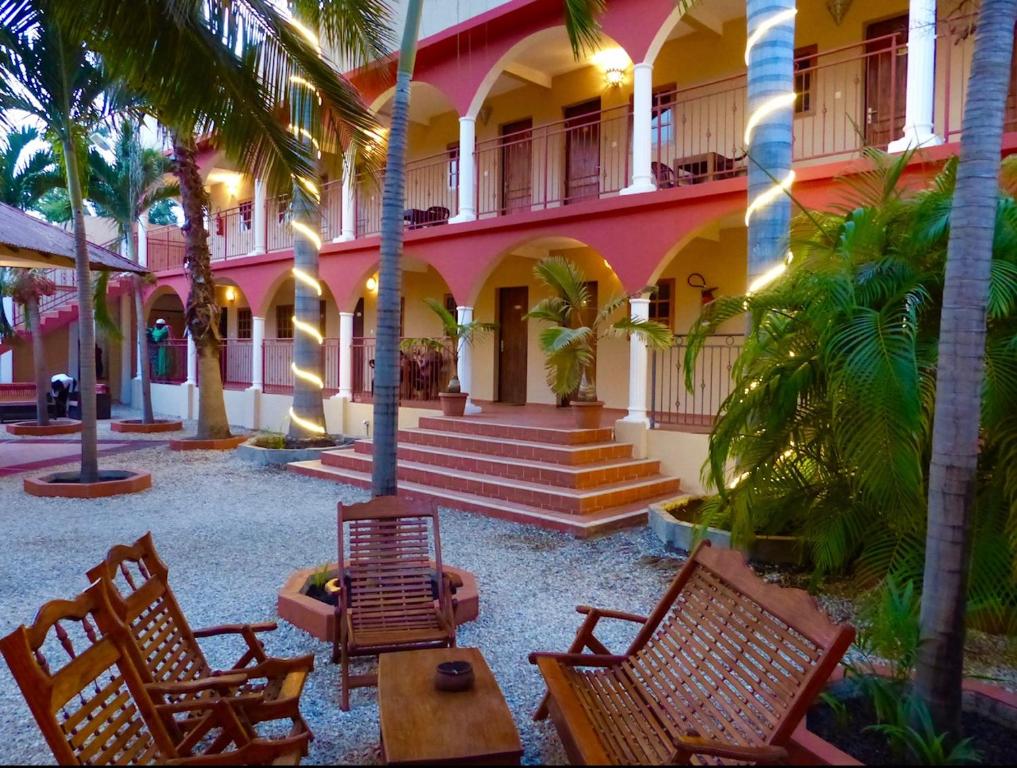 济金绍尔LES JARDINS DU FLAMBOYANT的一个带椅子的庭院和一座棕榈树建筑
