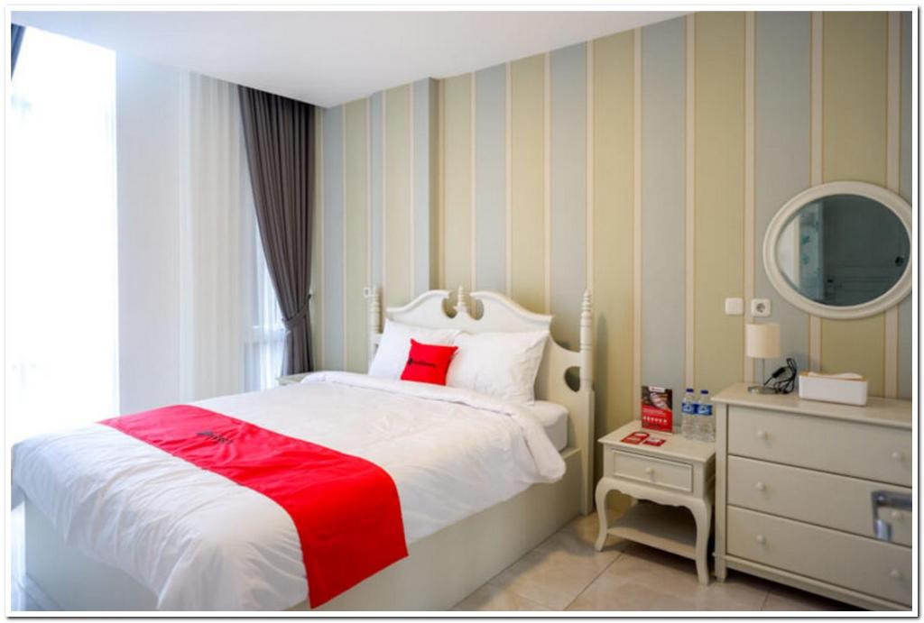 Kalibanteng-lorRedDoorz Plus @ Madukoro Raya Semarang的卧室配有红色和白色的床和镜子