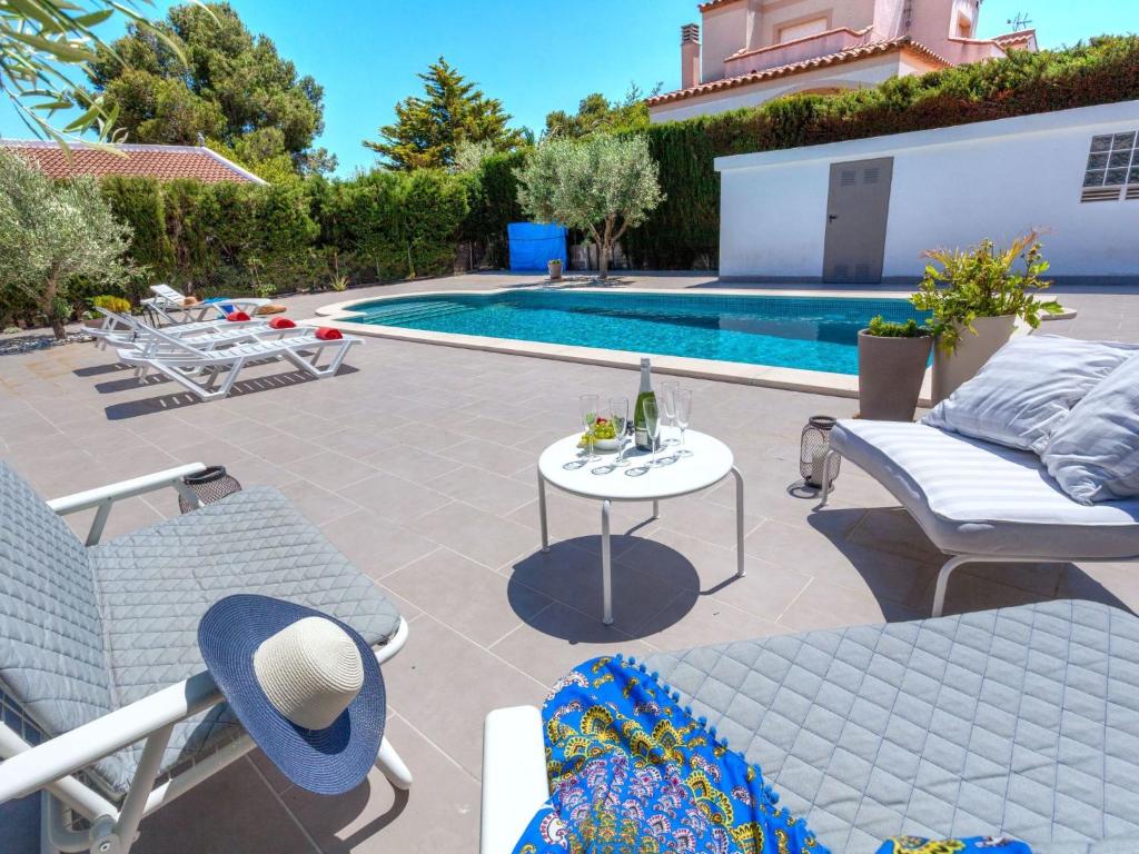 拉梅特拉·德·玛尔Villa Mercedes by Interhome的一个带椅子和桌子的庭院,毗邻一个游泳池