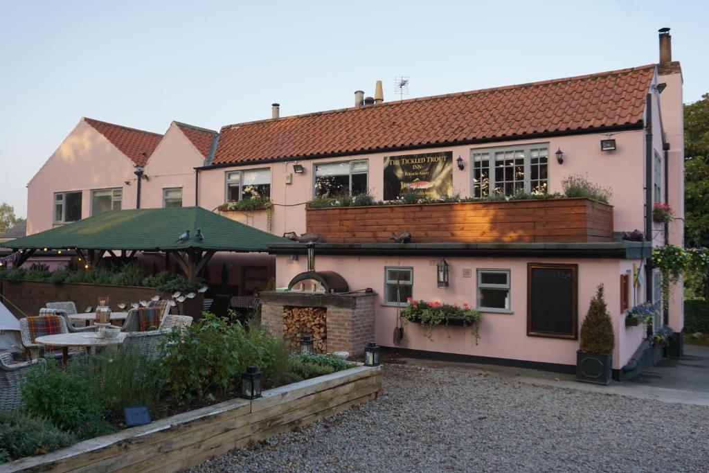 约克The Tickled Trout Inn Bilton-in-Ainsty的粉红色的房子,前面有一个花园