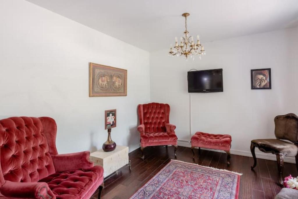 欧文Oasis 3 near DFW airport with Mediterranean setting的客厅配有2把红色椅子和电视