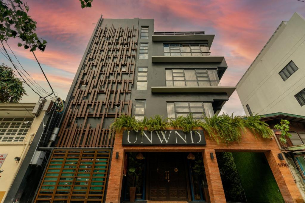 马尼拉UNWND Boutique Hotel Makati的一座高大的建筑,上面有读不想要的标志