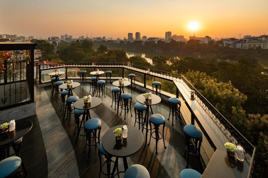 河内La Sinfonía del Rey Hotel & Spa的阳台上的一排桌子,享有日落美景