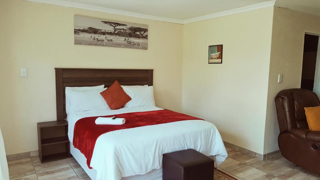 博克斯堡Carnival View Guest Lodge and spa的一间卧室配有一张带红色毯子和椅子的床
