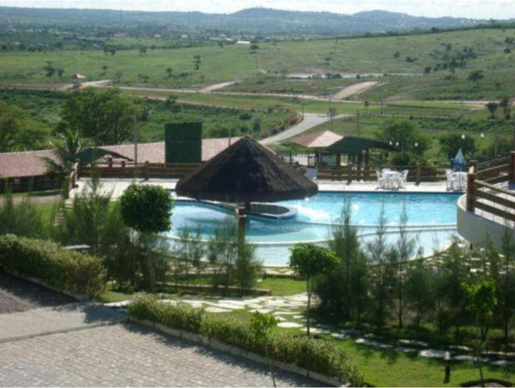 格拉瓦塔Flat Hotel Fazenda Monte Castelo - Gravatá的度假村内带草伞的游泳池
