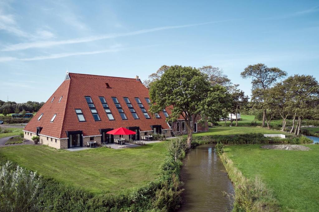 吕伐登Farm house Van der Valk Hotel Leeuwarden的河边一座红色屋顶的建筑