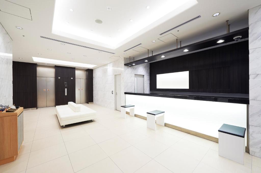 东京Sotetsu Fresa Inn Kanda-Otemachi的大堂设有白色沙发和大屏幕