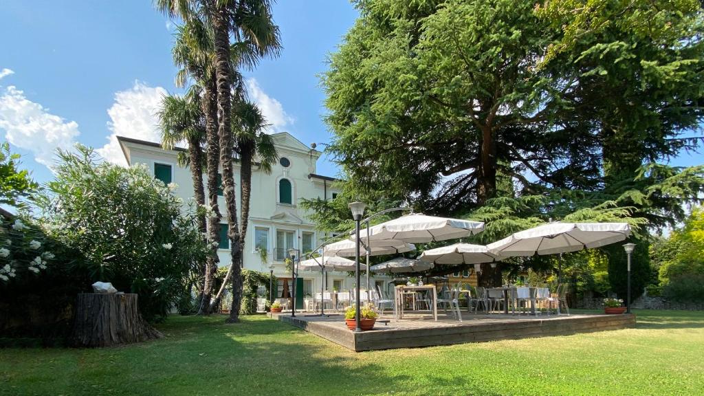 卡内瓦Villa Ca' Damiani Rooms & Apartments的院子内带桌子和遮阳伞的建筑