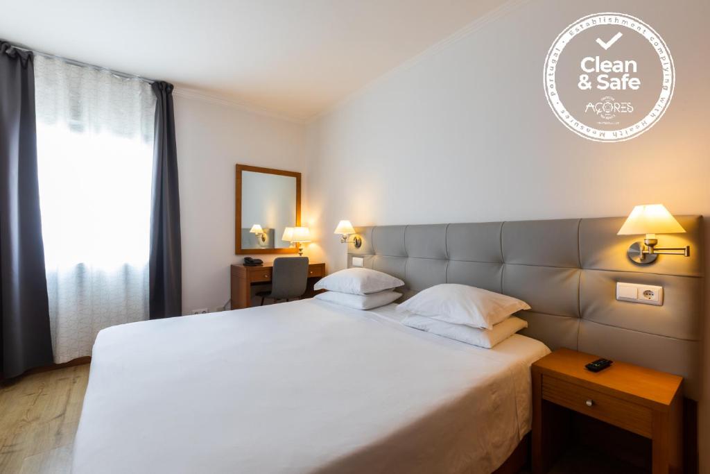 Rosário-Lagoa阿坎约酒店的卧室设有一张白色大床和一扇窗户。