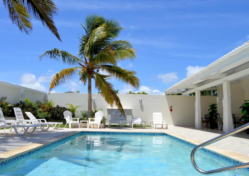 棕榈滩Yoyita Suites Aruba的一个带椅子的游泳池,并种植了棕榈树