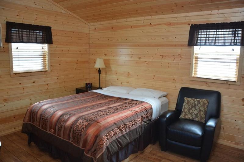 Watford CityRoosevelt Inn & Suites的一间卧室配有一张床和一把椅子,还有两个窗户