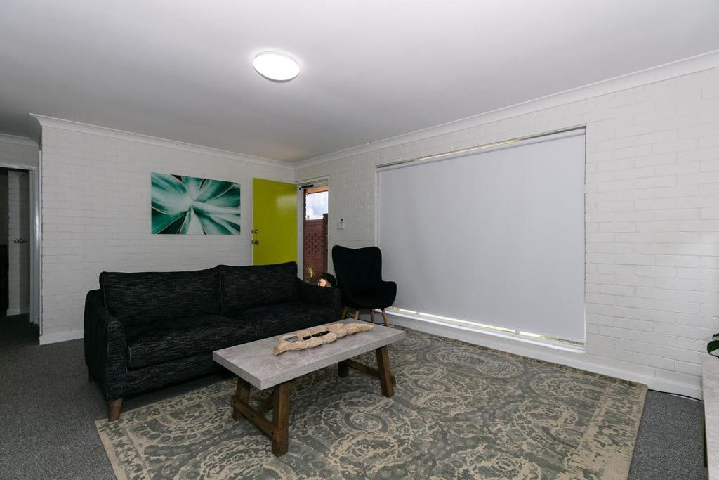 杰拉尔顿Apparition Apartments的客厅配有黑色沙发和桌子