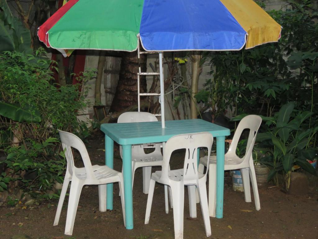 塔奈Perlies Inn Balcony House的一张桌子、四把椅子和一把伞