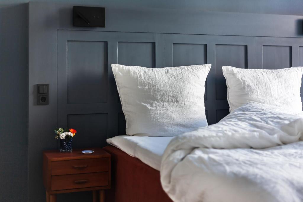 吕贝克Hotel Die Reederin的一间卧室配有两张带白色枕头的床和床头柜