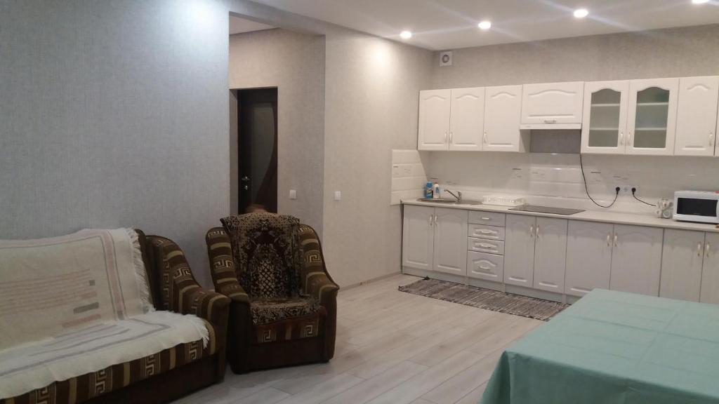 别列戈沃Будинок для гостей по вул. Шевченка的厨房配有白色橱柜、椅子和桌子