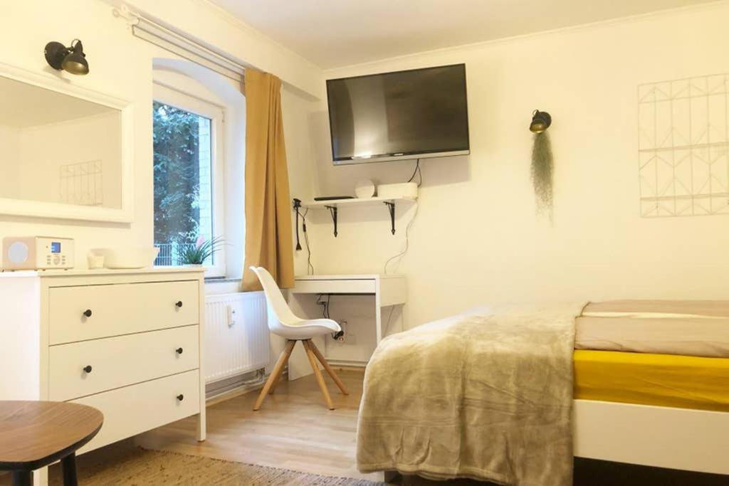 基尔Gemütliche sanierte 1 Zimmer Wohnung mit privatem Parkplatz im Zentrum的一间卧室配有一张床、一张书桌和一台电视。