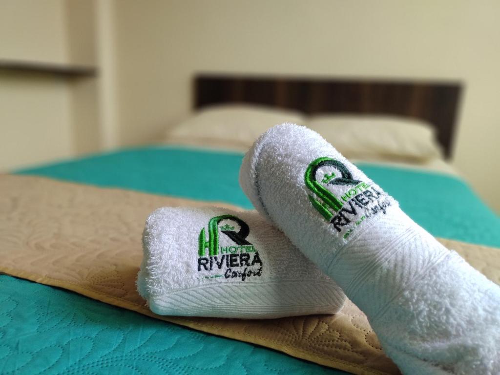 帕斯托Hotel Riviera Confort的两条滚毛巾(放置在床上)