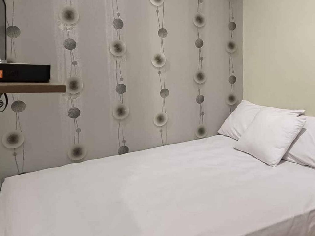 芝勒贡Aimer Guest House Syariah Mitra RedDoorz的一间设有球墙的房间的一张白色床