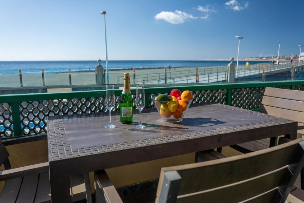 圣阿古斯丁Las Burras Beach terrace&pool By CanariasGetaway的一张桌子,上面放着一瓶葡萄酒和一碗水果