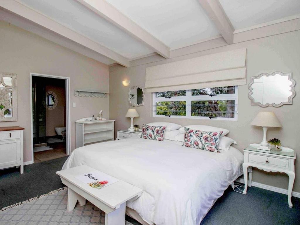 BergvlietCape Cottages的卧室配有一张白色的大床和两张桌子