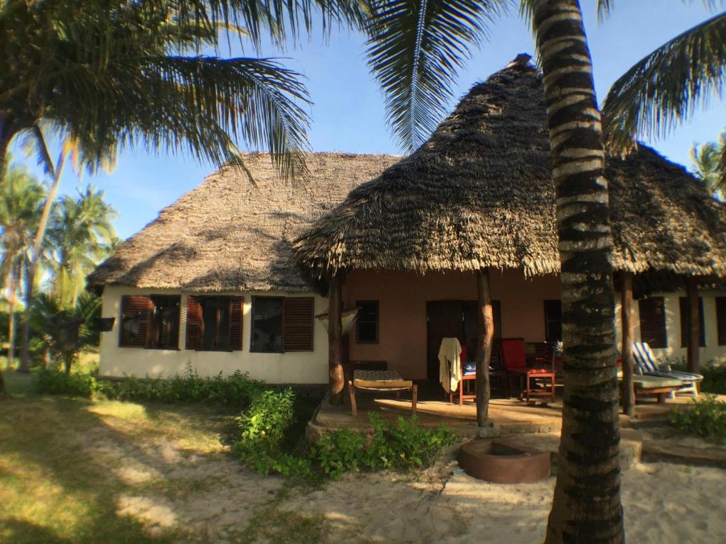 Ushongo MabaoniEmbedodo Beach House, Ushongo beach, Pangani的茅草屋顶和棕榈树的房子