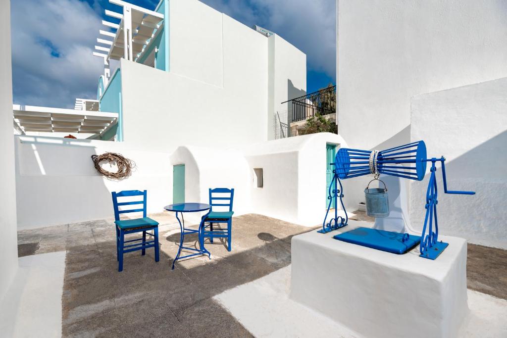 费拉Authentic Santorinian Home Experience的一组蓝色椅子和一张桌子,位于大楼前