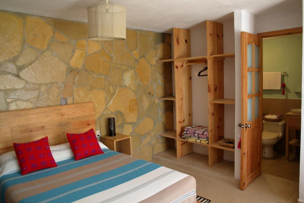 圣克里斯托瓦尔-德拉斯卡萨斯Gaia Guest House的一间卧室设有一张床和石墙