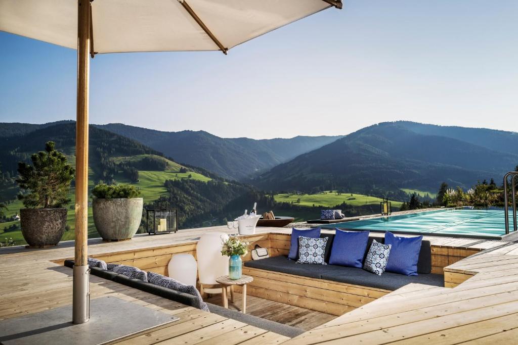 莱奥冈BergWärtsGeist SENHOOG Luxury Holiday Homes的一个带沙发和遮阳伞的泳池甲板